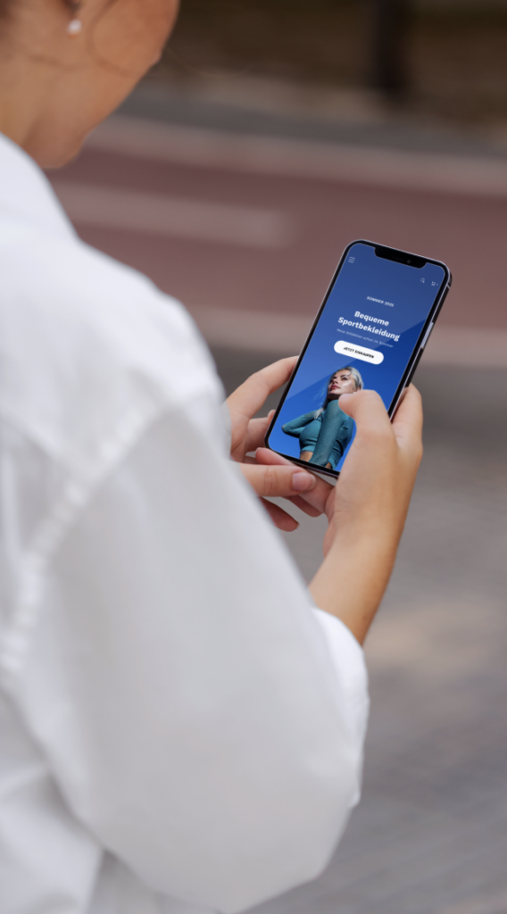 Person hält Smartphone mit Anzeige für bequeme Sportbekleidung und einem Foto einer Frau in Sportkleidung