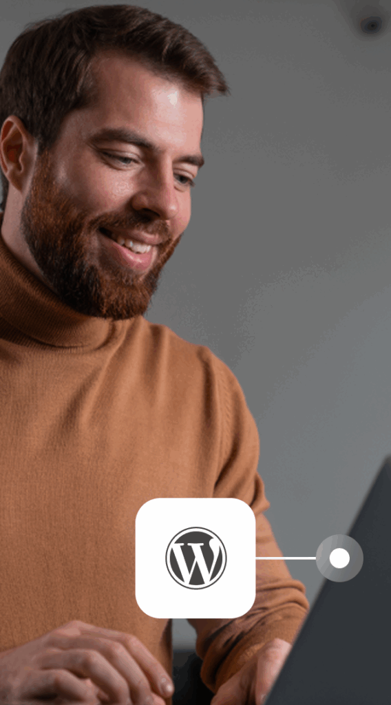 Lächelnder Mann in braunem Rollkragenpullover arbeitet am Laptop mit WordPress-Logo eingeblendet