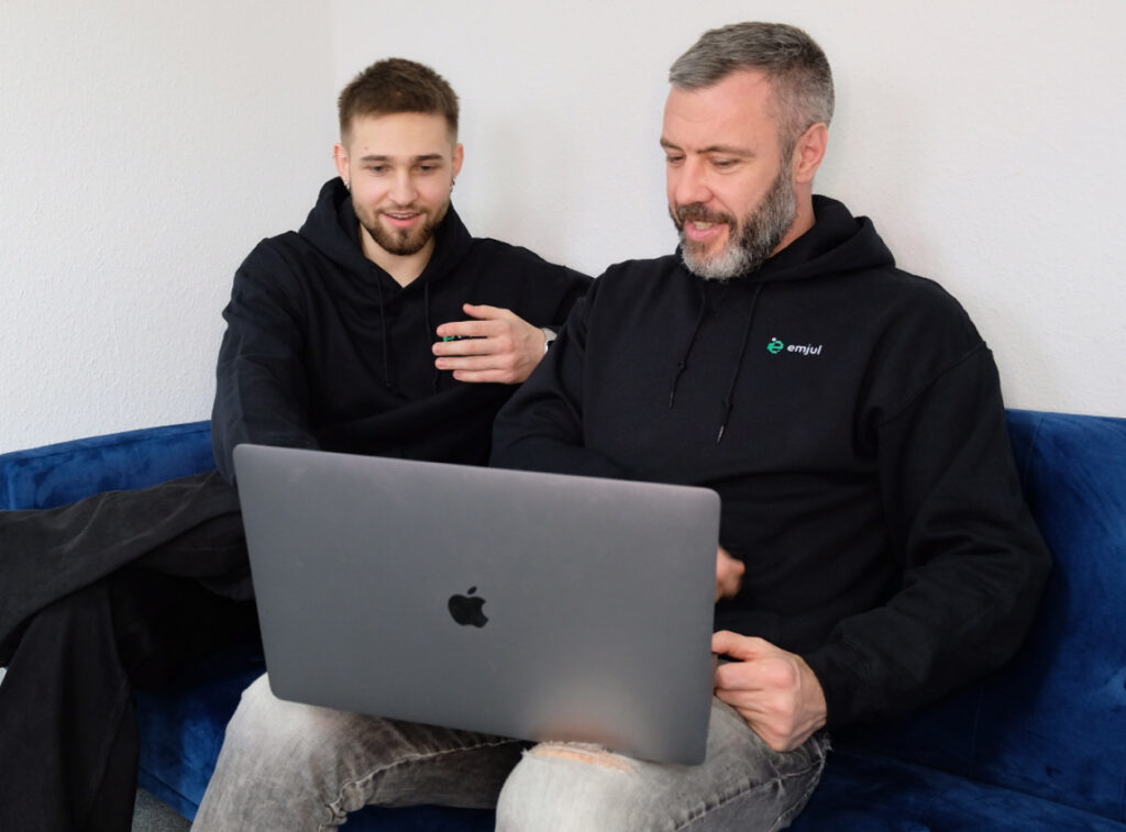 Zwei Teammitglieder von design030 sitzen auf einem blauen Sofa. Sie wirken konzentriert und im Austausch über ein digitales Projekt.