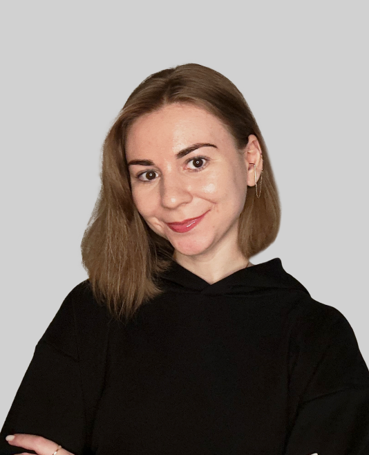 Junge Frau mit mittellangen braunen Haaren und schwarzem Hoodie vor grauem Hintergrund